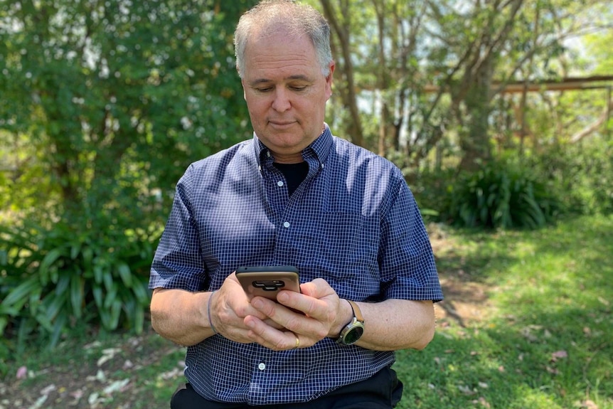 Greg Todd looks at his mobile phone.