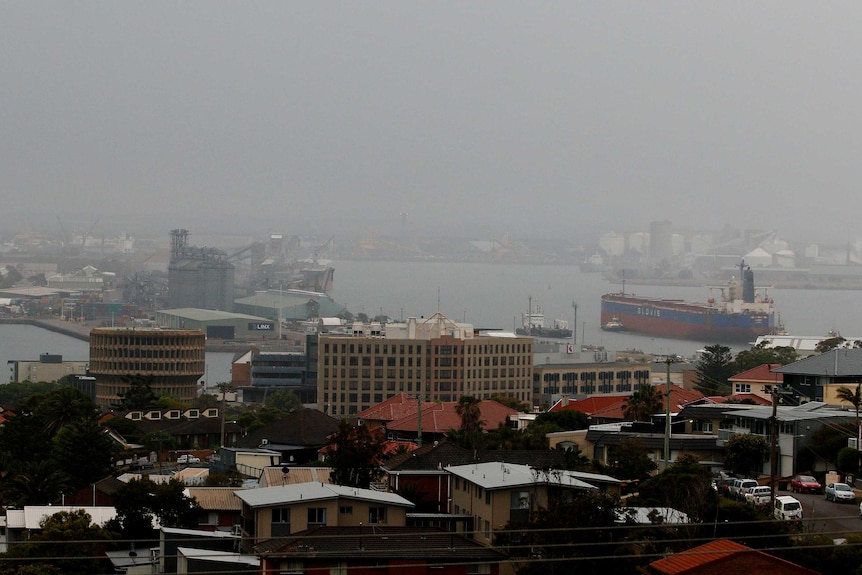 Кораб за въглища влиза в пристанището на Нюкасъл срещу мрачното сиво небе в Сидни, докато градът е очукан от дъжд.