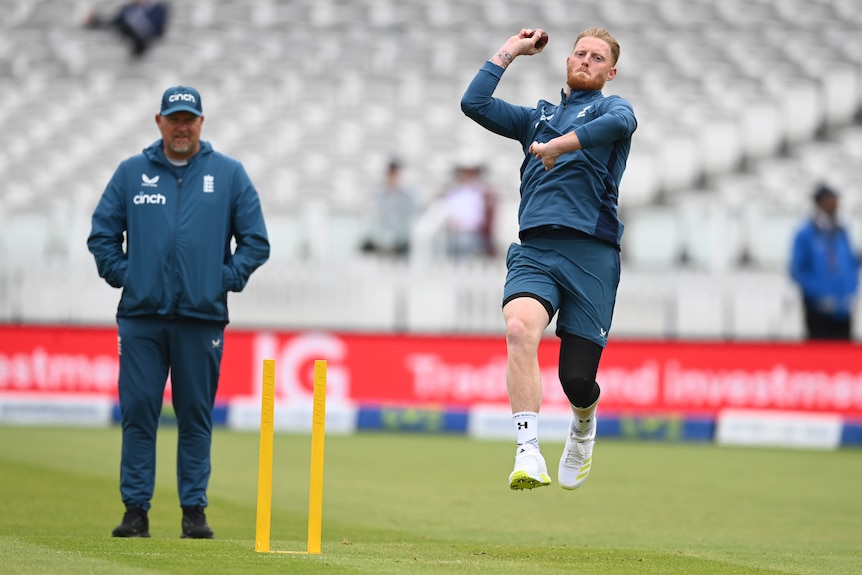 Ben Stokes bowls in training kit with a man standing behind him watching