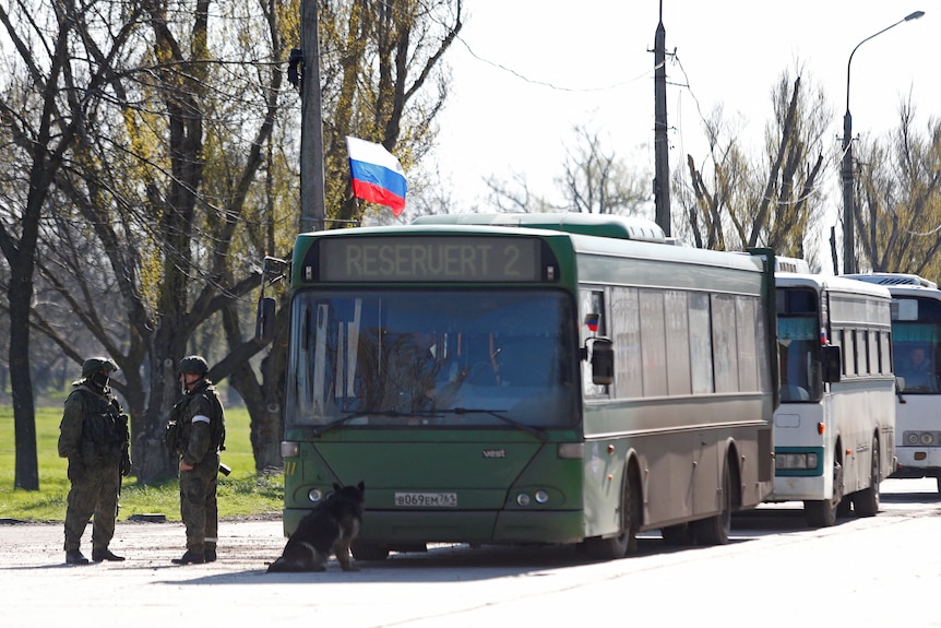 Pro-Russian troops stand beside evacuation buses in Mariupol.