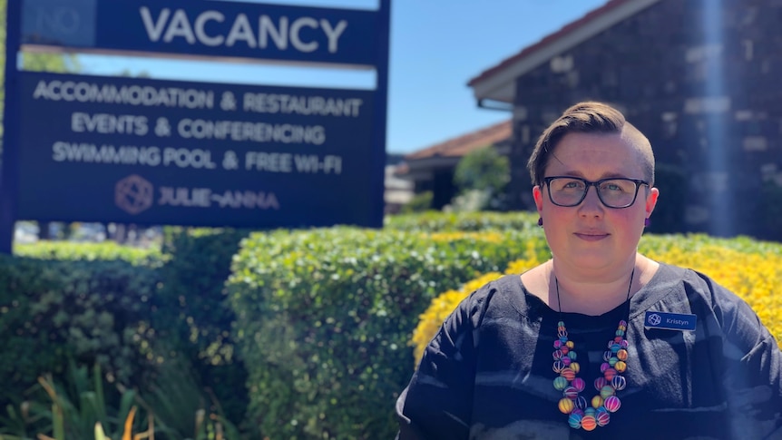 Woman stands in front of hotel sign