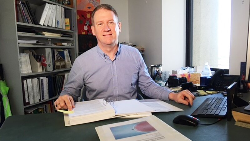 Family and fertility lawyer Stephen Page sits at his office desk with books and papers.
