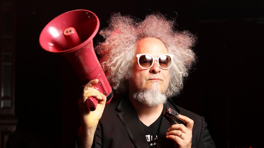 Sxip Shirey holds a megaphone while wearing sunglasses.