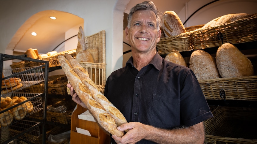 Man holds French sticks in bakery