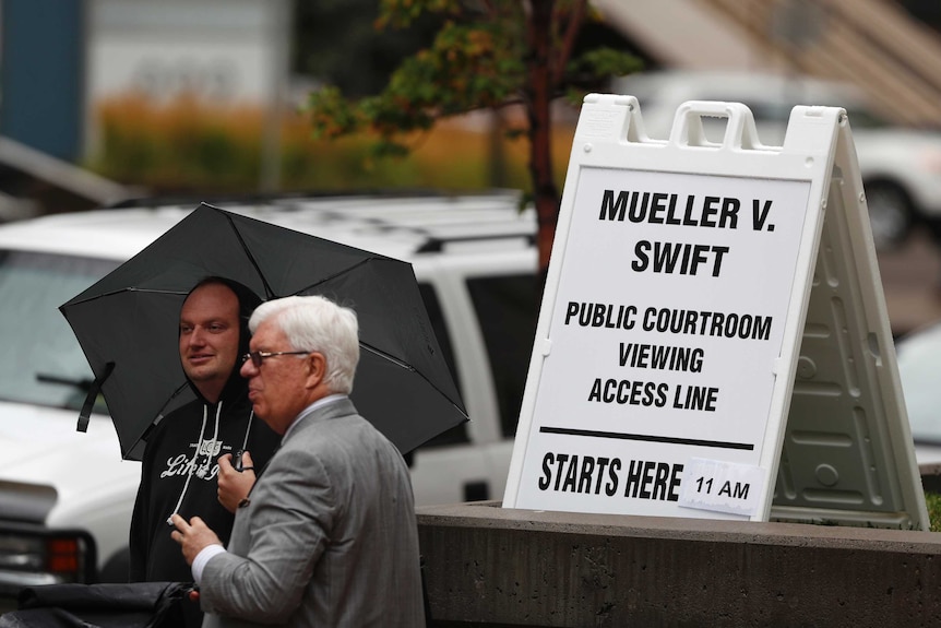 Two men stand in line waiting to attend the jury selection phase.