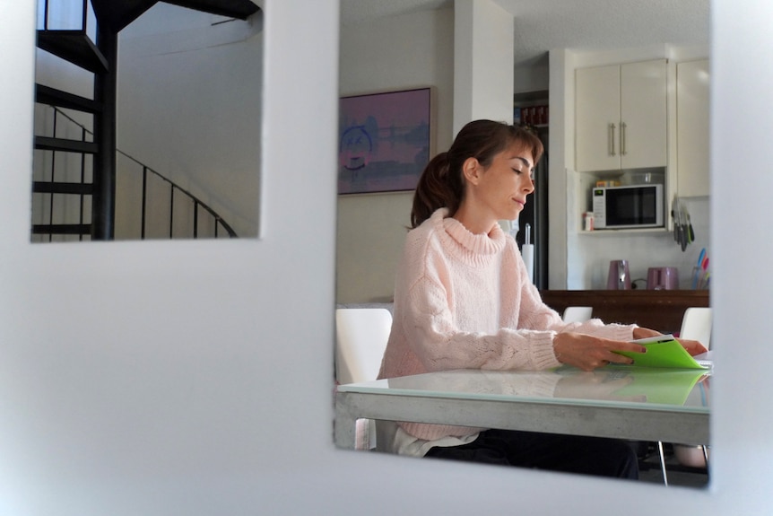 Sarah Kay sits at her white kitchen table, looking through documents.