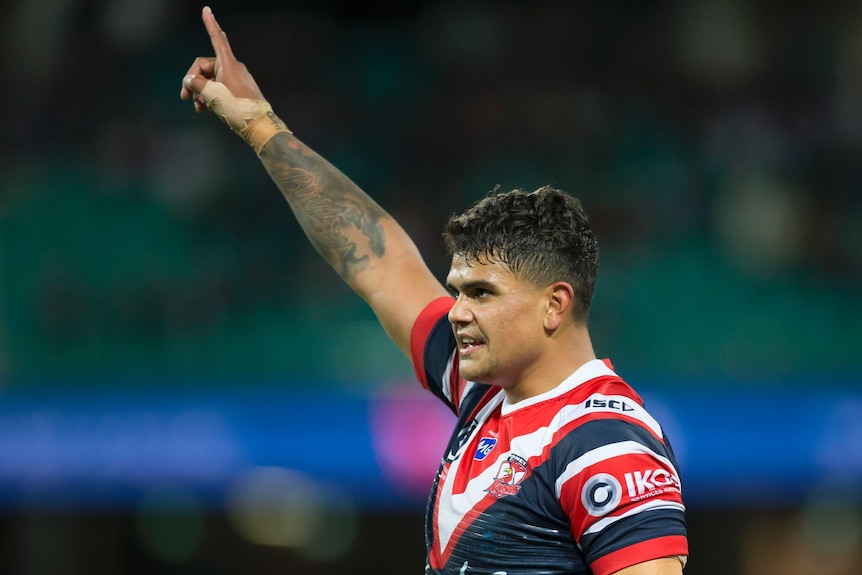 Latrell Mitchell points a finger on his raised right arm as he celebrates the Roosters' win over the Tigers.