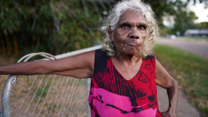 A woman leaning on a fence.