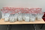 Multiple police evidence bags filled with methamphetamine sitting on a table.