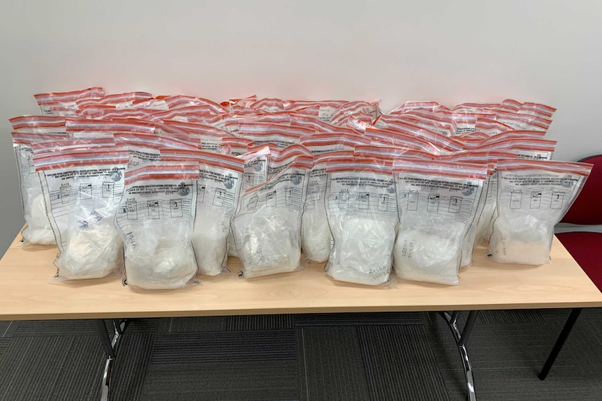 Multiple police evidence bags filled with methamphetamine sitting on a table.