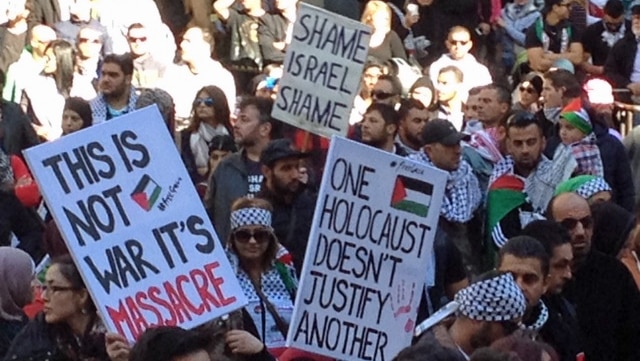 Members of the crowd holding signs at a pro-Palestinian rally in Sydney.