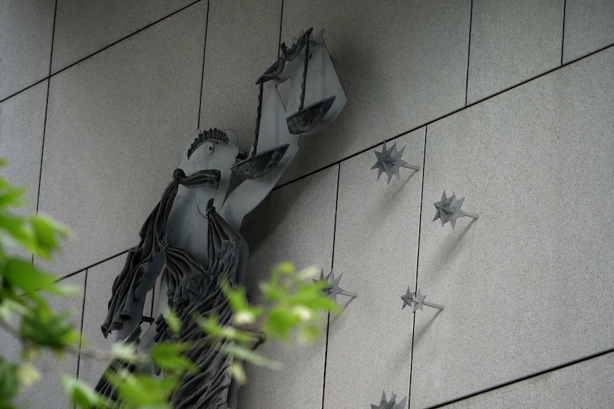 Metal artwork of a woman dressed in robes and holding the scales of justice alongside the Victorian Southern Cross.
