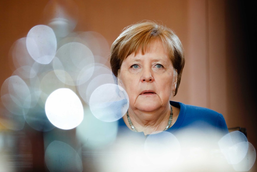 German Chancellor Angela Merkel is seen with a reflection of a pot in the foreground.