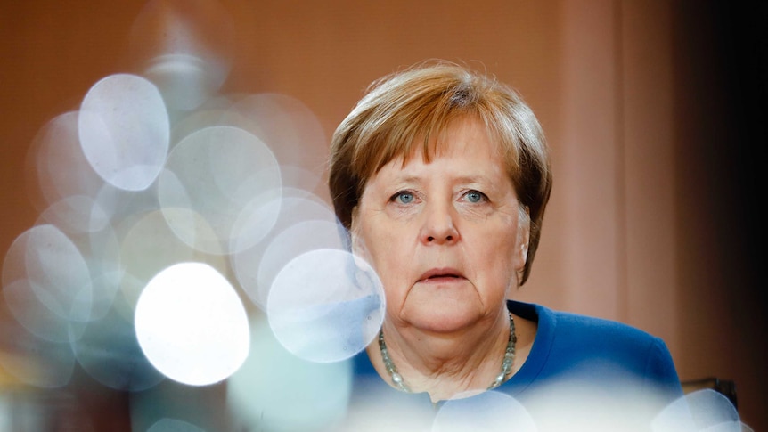 German Chancellor Angela Merkel is seen with a reflection of a pot in the foreground.