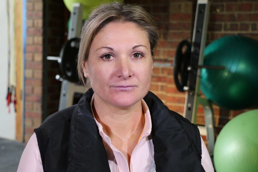 Personal trainer Kylie Willey, in a gym, looks at the camera.