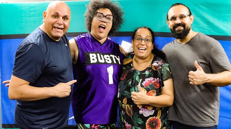 Four comedians pose for picture in front of a Torres Strait flag