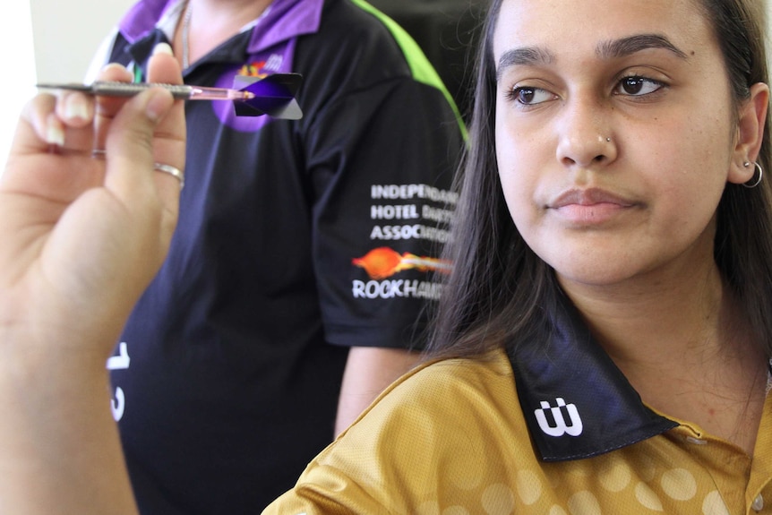 Indigenous dart player Kyla Ahmann holds a dart and is ready to throw it