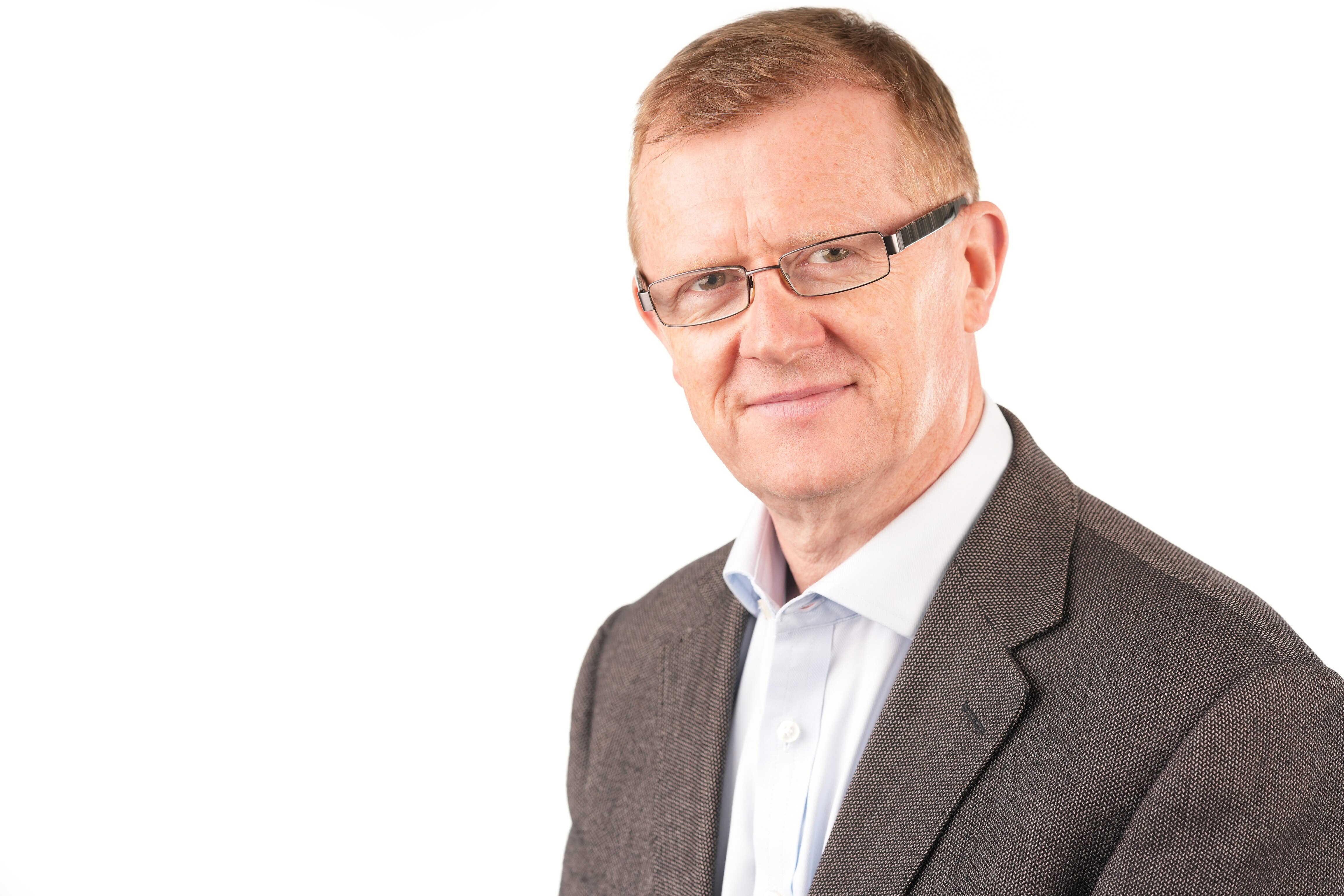 Hombre de mediana edad con chaqueta de traje marrón y camisa blanca con gafas  
