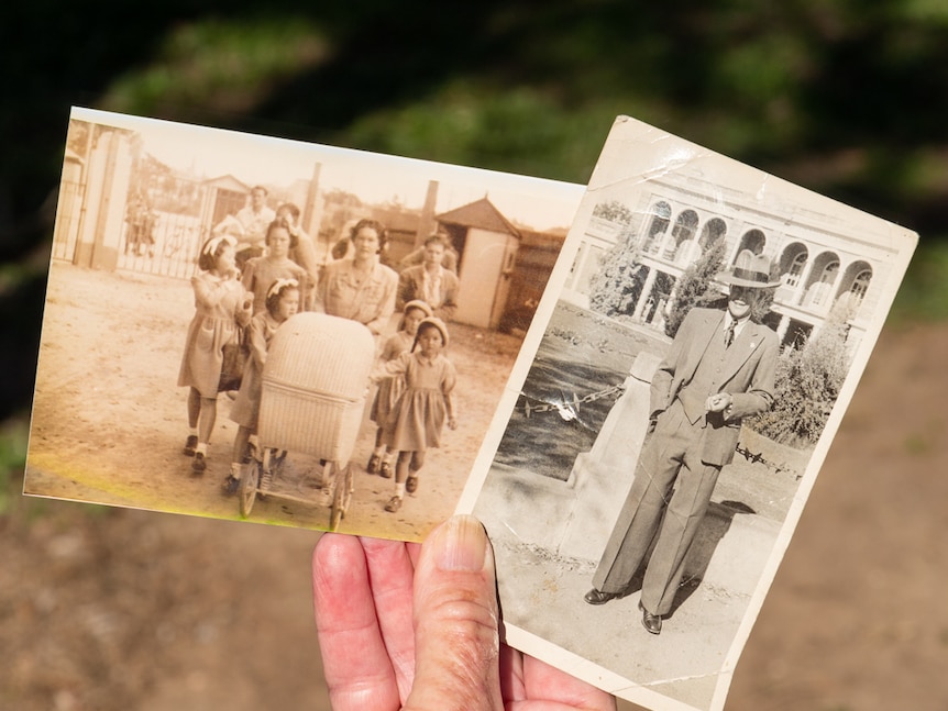 A woman's hand holding two photographs featuring family members.