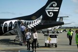 People board a Air New Zealand plane on a tarmac