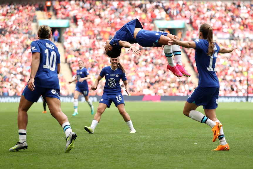 Sam kerr is mid-backflip with Chelsea teammates around her after a goal in the Women's FA Cup final.