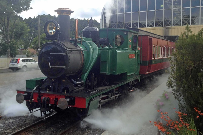 A steam engine train leaves a station.