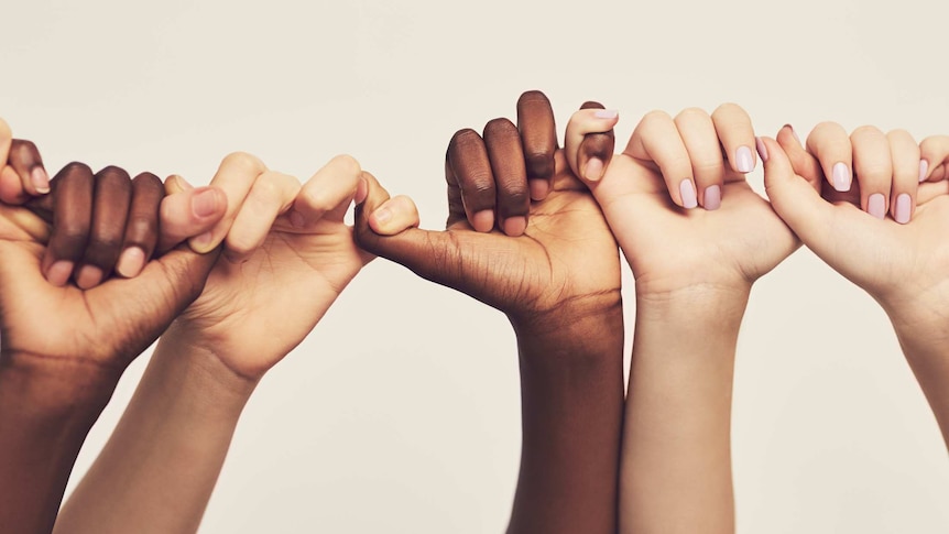 Hands of people of different ethnicities linked fingers in a line