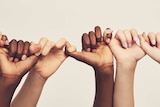 Hands of people of different ethnicities linked fingers in a line