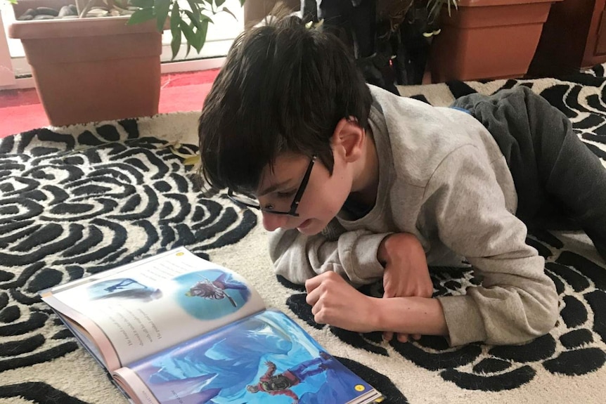 Joe Lockwood reads a book on the floor during self-isolation at home.