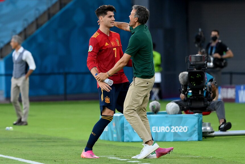 A striker and his team manager hug near the sideline after he scores a goal at Euro 2020.