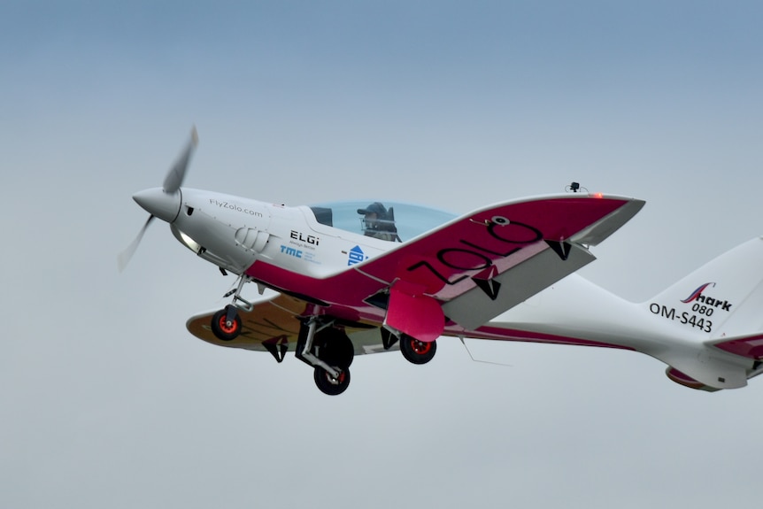 Woman in a microlight plane with has zara zolo on the underwings as it takes over. 