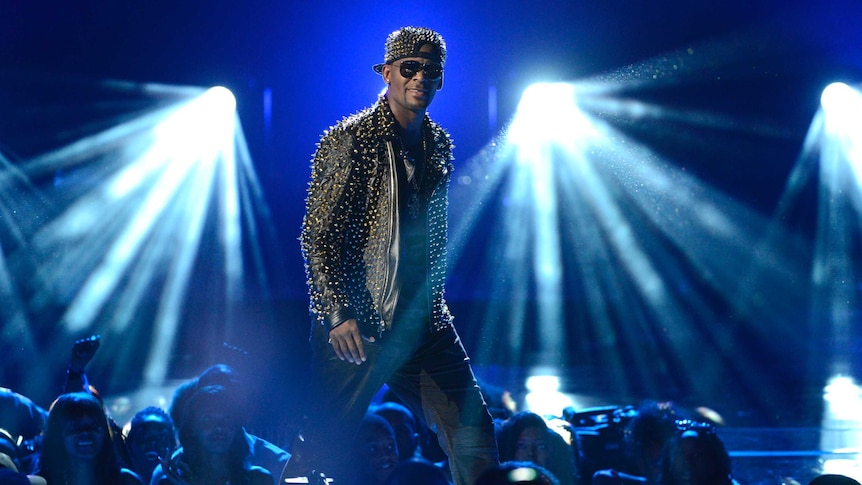 R. Kelly wears a studded jacket while performing on stage.