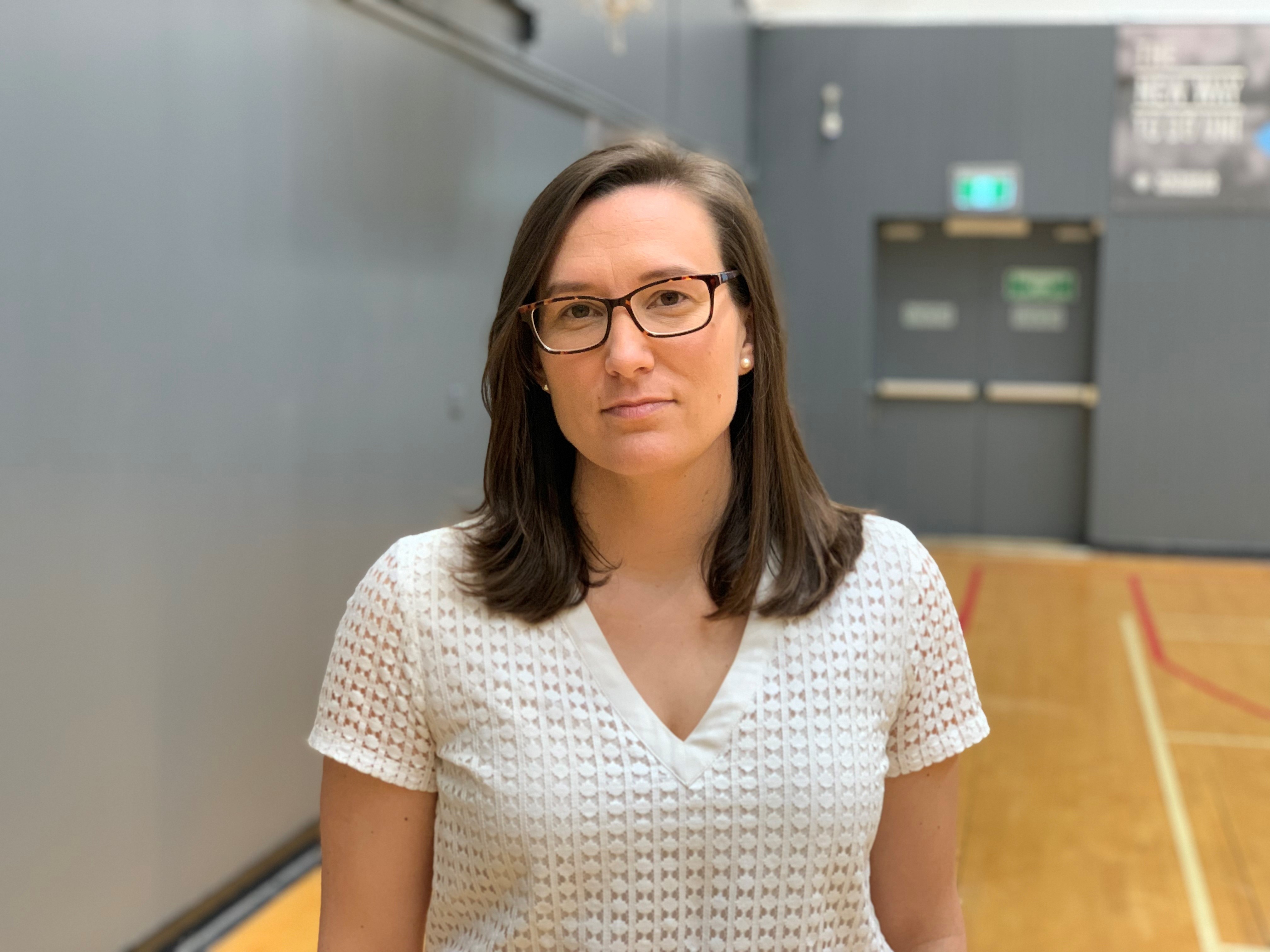 Dr Mary Woessner poses for a photo on one of the basketball courts at Victoria University.