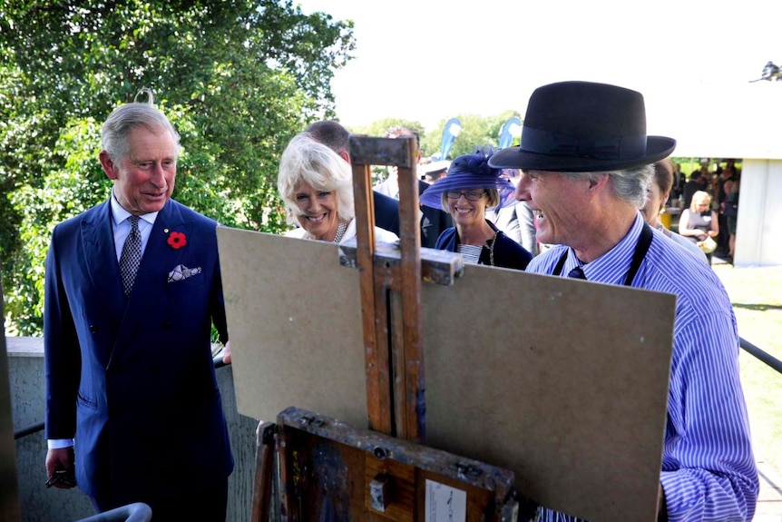 Prince Charles admires an artwork of Warwick Fuller on a canvas.