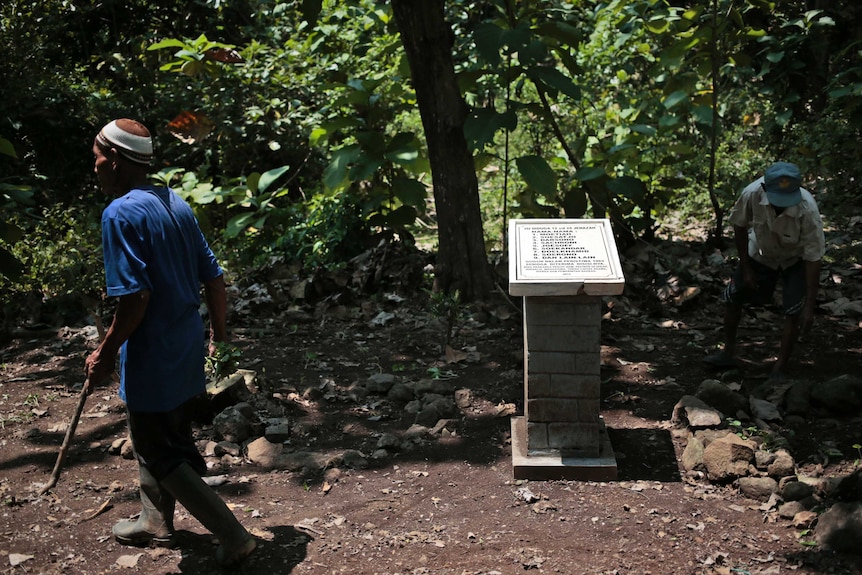 Eye witnesses to the aftermath of the massacre tend to the monument at a mass grave in Central Java.