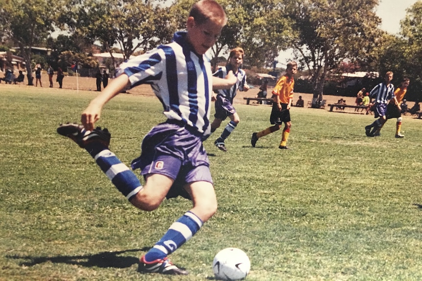 A young boy kicks a soccer ball on a grassy field.