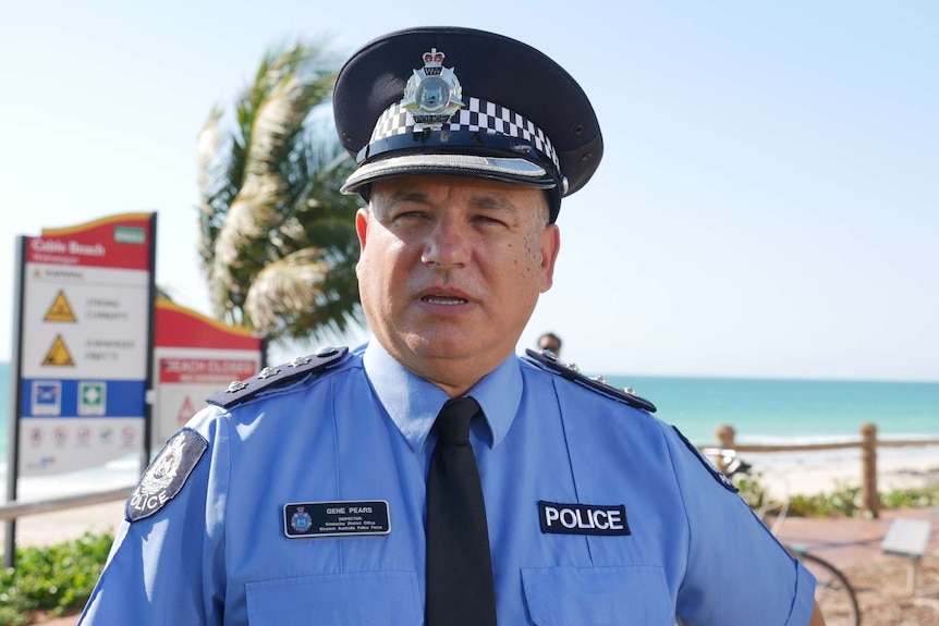A policeman speaking to media at a press conference on a beach