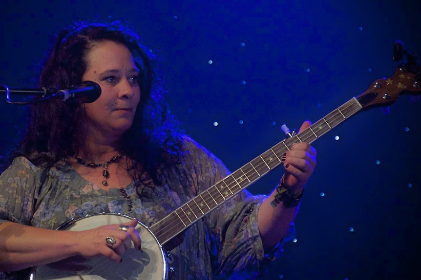 woman with curly brown hair holding a banjo