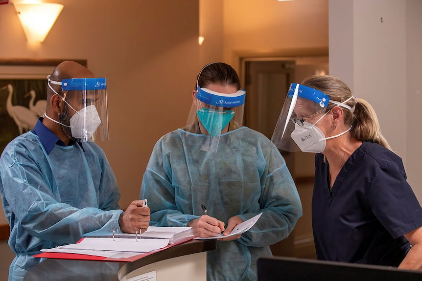 An Australian Army officer talks with two nurses at an aged-care facility