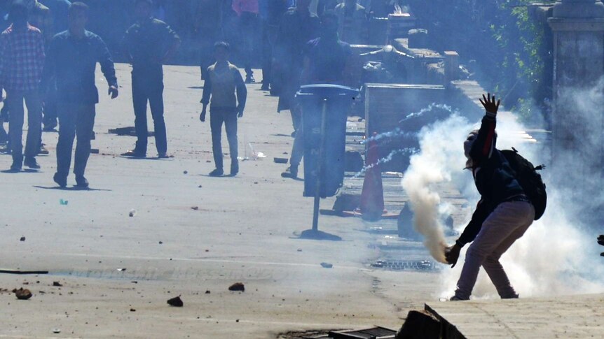 A masked Kashmiri Muslim protester throws exploded tear gas shell back at Indian police.