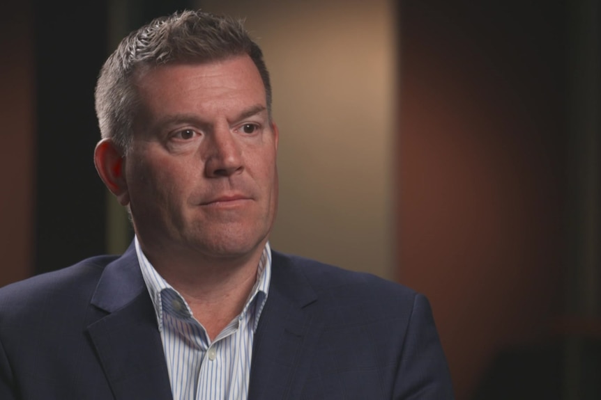 Man wearing a suit sitting down for an interview.