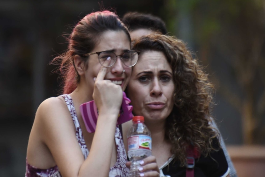 A woman wipes tears from her eyes.