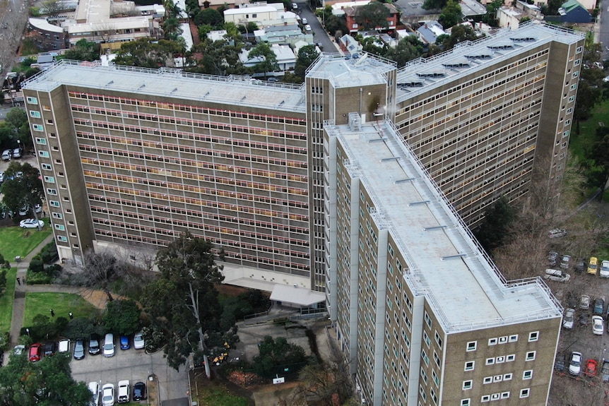 On an overcast day, you view a y-shaped public housing tower with an open-air carpark surrounding it.