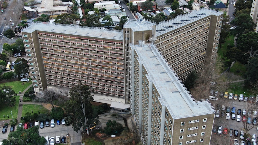 On an overcast day, you view a y-shaped public housing tower with an open-air carpark surrounding it.