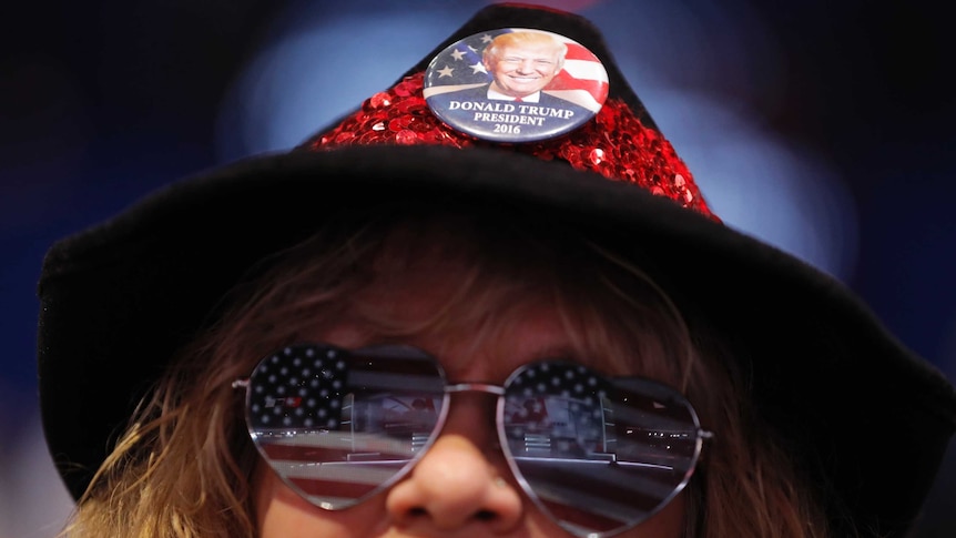 A woman wears US flag-themed eyeglasses and a button supporting Donald Trump.