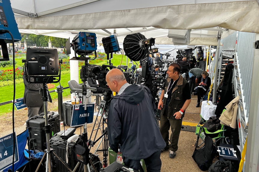 Inside of a pop-up tent with TV cameras, lights and crews.