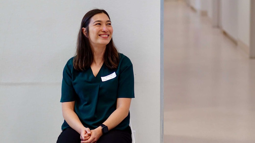 Rachelle Kalic sits on a chair in a hospital hallway