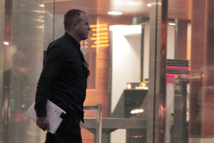 Brett Spits exits the glass doors outside the County Court in Melbourne.
