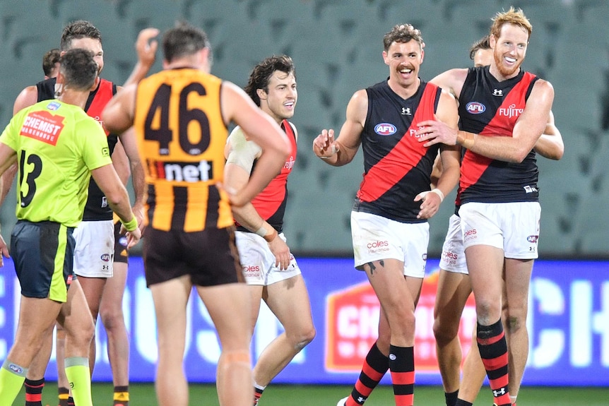 A group of Essendon AFL players celebrate a goal against Hawthorn.