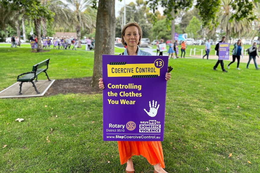 A campaigner holds a placard about coercive control.